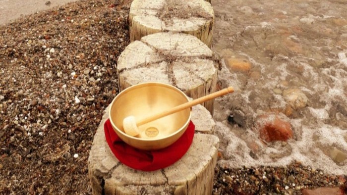 Ein goldener Becher mit einem Löffel steht auf einem Holzstumpf am Strand