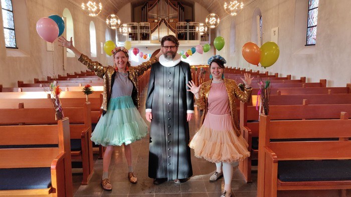 To børn og en mand i kirke med balloner
