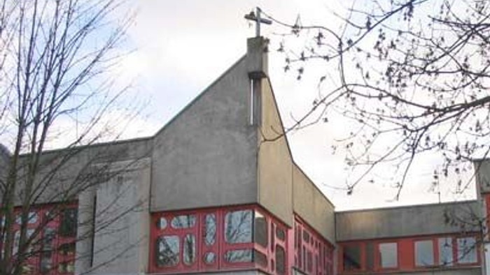 Kirchliches Gebäude mit rotem Zierwerk und Kreuz auf dem Dach