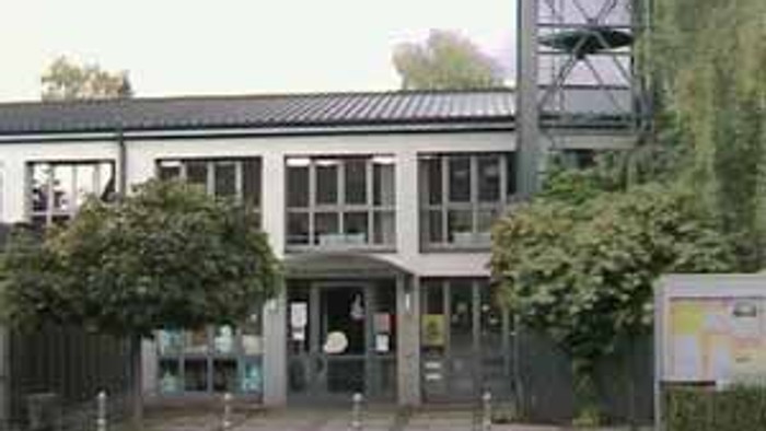 Das Bild zeigt ein modernes Gebäude mit einem hohen Turm und umgeben von Bäumen.