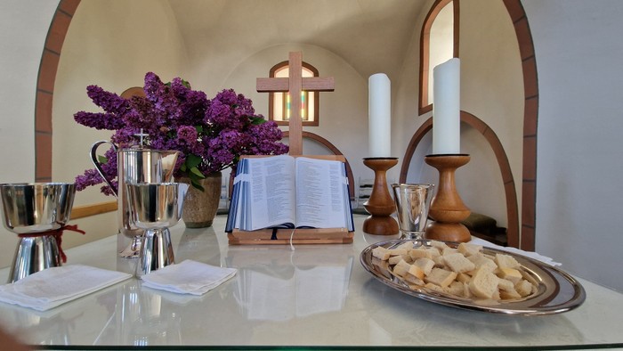 Ein Tisch mit Kerzen, Buch, Blumen und Gebäck in einem gemütlichen Raum