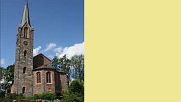 Ein steinernes Kirchengebäude mit hohem Turm und spitzem Dach vor einem bewölkten Himmel.