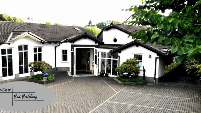 Ein modernes, weißes Gebäude mit großen Fenstern und einem gepflegten Garten.