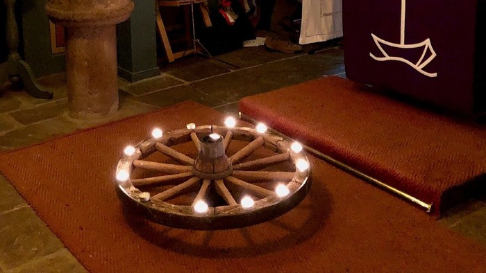 Kircheninneres mit brennenden Kerzen und betenden Menschen