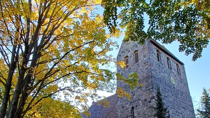Dorfkirche Marienfelde umgeben von Bäumen mit Herbstlaub
