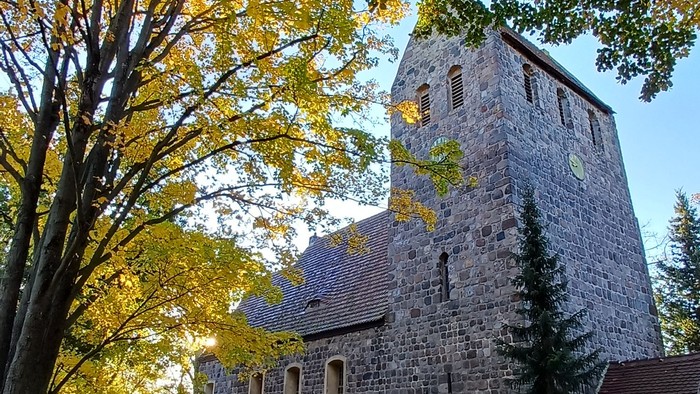Dorfkirche Marienfelde umgeben von Bäumen mit Herbstlaub