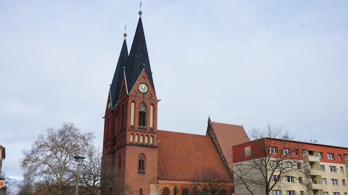Friedenskirche. Klassischer Backsteinbau mit Satteldach und zwei spitz zulaufenden Türmen.