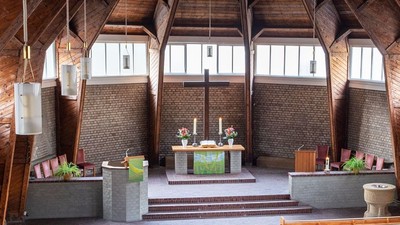 Ein moderner Wohnraum mit hohen Decken und großen Fenstern, eingerichtet mit Holz und grünen Akzenten.