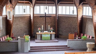 Ein moderner Wohnraum mit hohen Decken und großen Fenstern, eingerichtet mit Holz und grünen Akzenten.