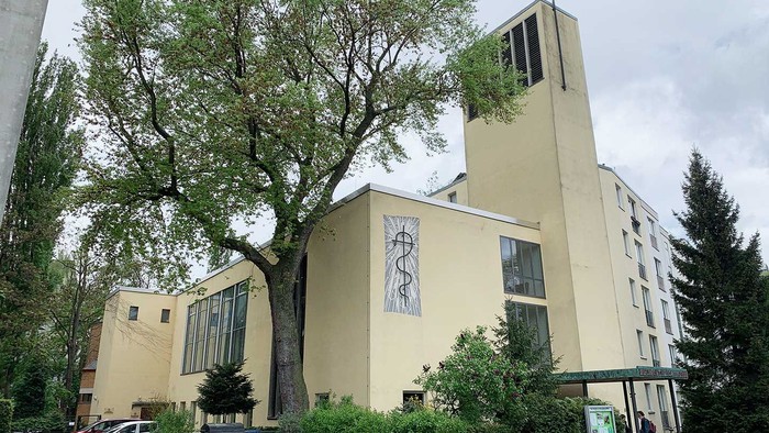 Gelbe Kirche mit hohem Baum und Auto davor