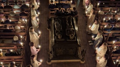 Viele Menschen sitzen in einer Kirche und halten Kerzen