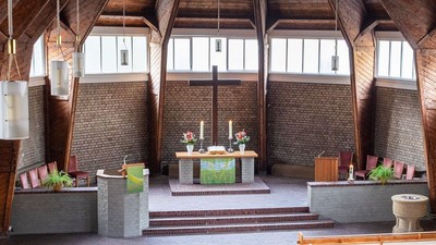 Ein moderner Wohnraum mit hohen Decken und großen Fenstern, eingerichtet mit Holz und grünen Akzenten.