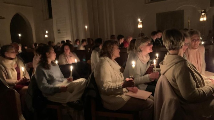 Eine Gruppe von Menschen sitzt in einer Kirche und hält Kerzen.