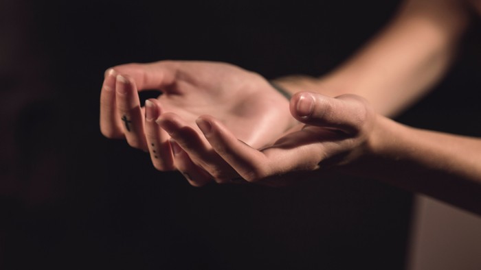 Two hands gently touching, one palm facing up, the other resting on top.