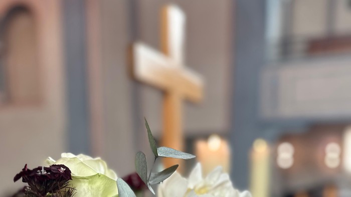 Blumenstrauß vor Kreuz in Kirche