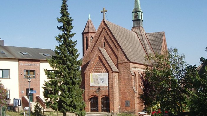 Kirchengelände mit Kopfsteinpflasterweg und Bäumen