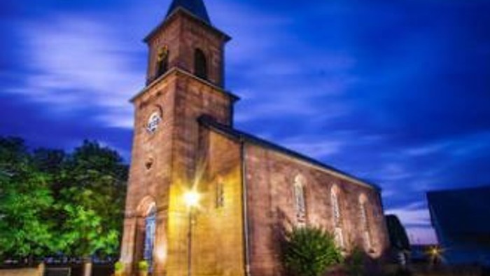 Eine Kirche mit einem Uhrturm, die nachts beleuchtet ist.