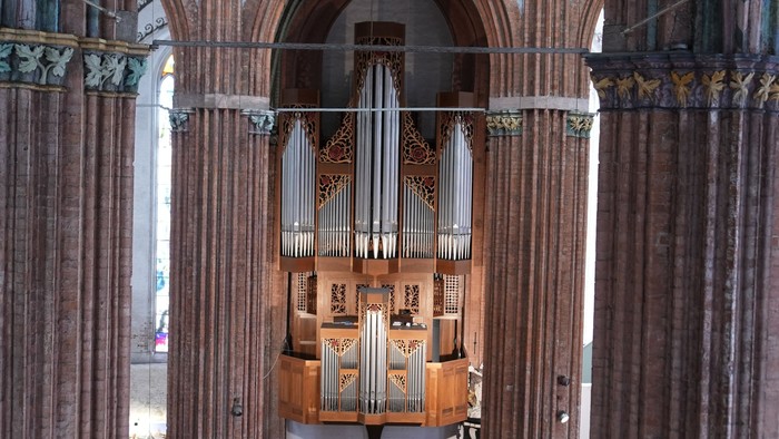 Großes Kircheninnere mit hölzernen Bänken und Orgel.