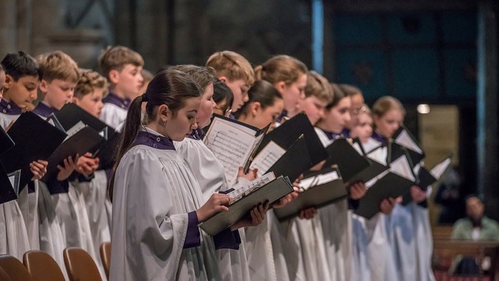 Eine Gruppe junger Sänger in Chorroben, die in einer prächtigen Kathedrale Musik aufführen.