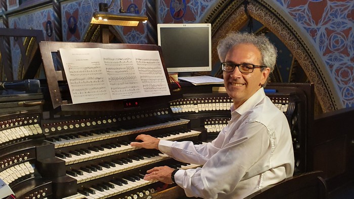 Ein Mann spielt eine verzierte Pfeifenorgel in einem wunderschön gestalteten Kircheninneren.