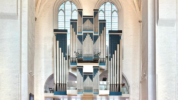 Eine große Kirche mit einem großen Orgel und vielen Menschen auf Bänken.