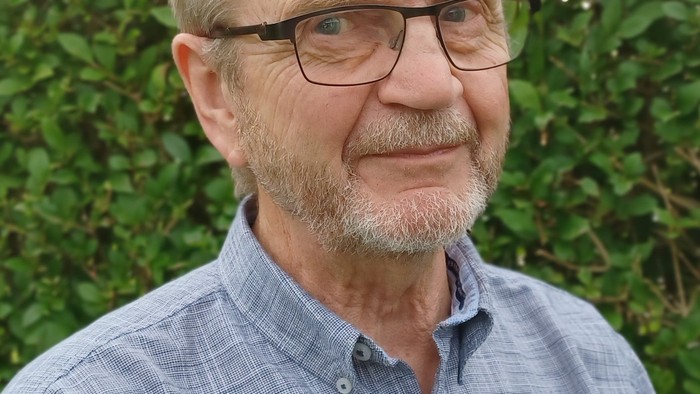 En ældre mand med blond hår og briller, der kigger direkte i kameraet.