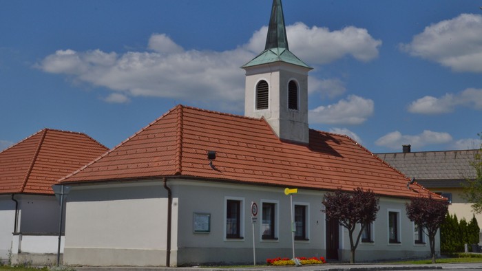 Kirche mit hohem Turm und rotem Dach unter blauem Himmel