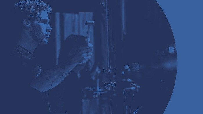 En person betjener avanceret laboratorieudstyr under Pulsar 2023-arrangementet.