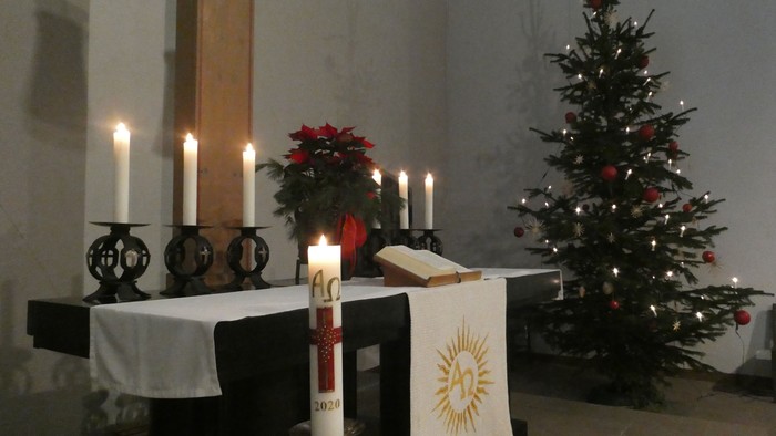 Weihnachtsdekoration in der Kirche mit Kerzen, Tannenbaum und Poinsettien