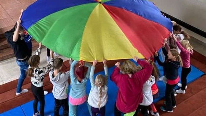 Kinder spielen in einem Raum mit einem bunten Parachute