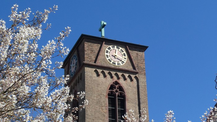 Ein Ziegeluhrenturm mit weißer Kirschblüte im Vordergrund