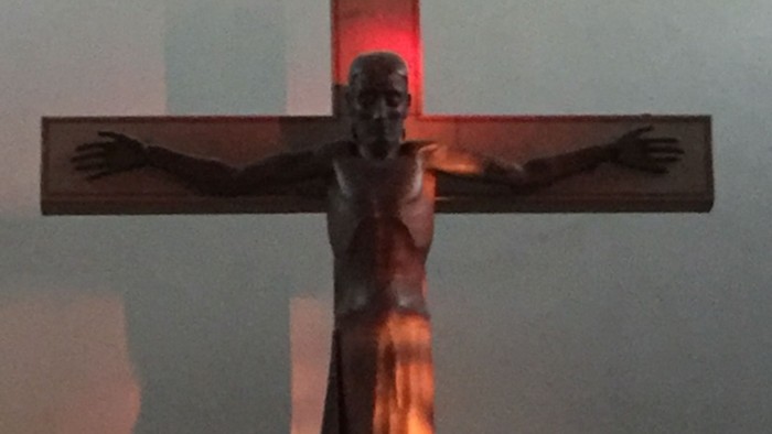 Ein Kruzifix mit Jesusfigur vor einem beleuchteten Hintergrund