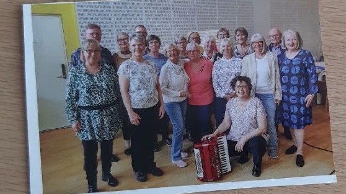 En gruppe af kvinder samlet i et rum med en kvinde med akkordeon i forgrunden