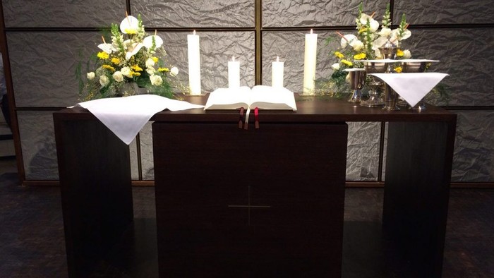 Ein Altar mit zwei Kerzen, einem Buch und zwei Blumenarrangements