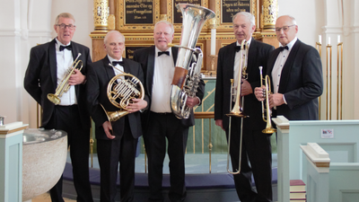 Gruppe af mænd i jakkesæt, der holder messingblæseinstrumenter.