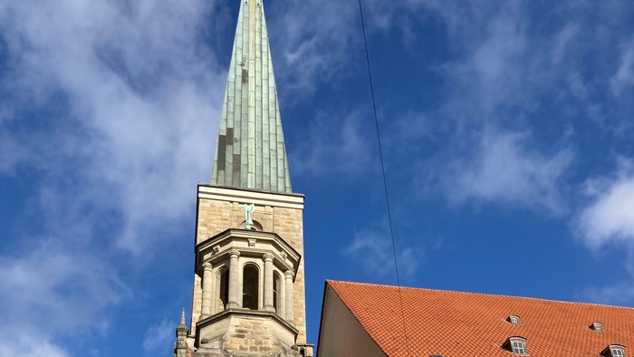 Kirchturm mit spitzer Spitze und roter Ziegeldachkirche, Baum mit roten Blättern