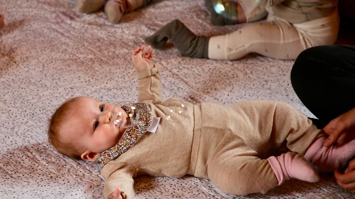 en baby der ligger på et gulv med sæbebobler svævende over sig