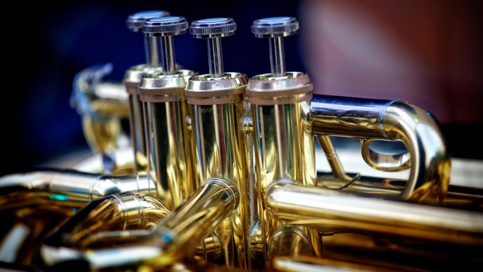 Nærbillede af polerede messingventiler og skydere på en trompet, der glimter i lyset.
