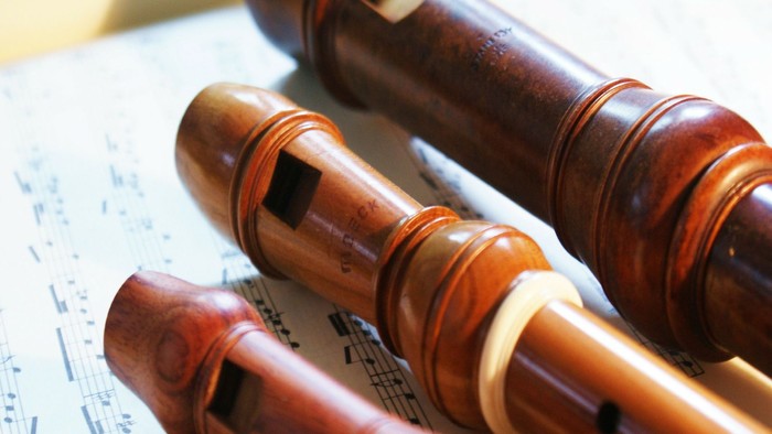 Drei Holzflöten liegen auf Notenblättern