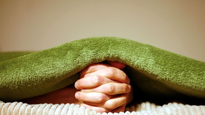 Eine Person versteckt ihr Gesicht unter einem grünen Handtuch.