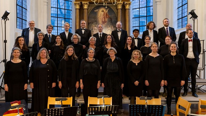 Ein Chor steht in einer Kirche vor Notenständern und einem Altar.