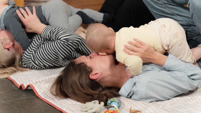 Familie leger sammen på gulvet med legetøj.