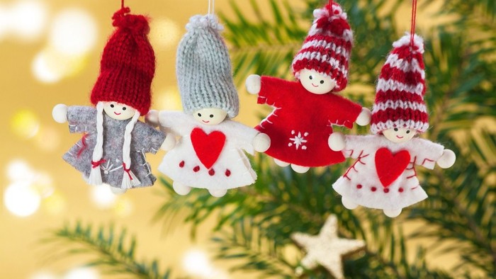 Fire festlige julepynt hænger på et juletræ, hver med et strikket hat- og hjerte-design.