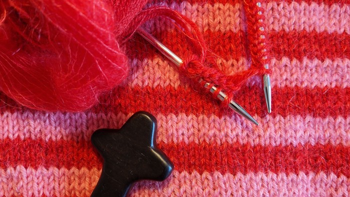 En håndklæde i røde og orange striber med en svart korset knap og strå.