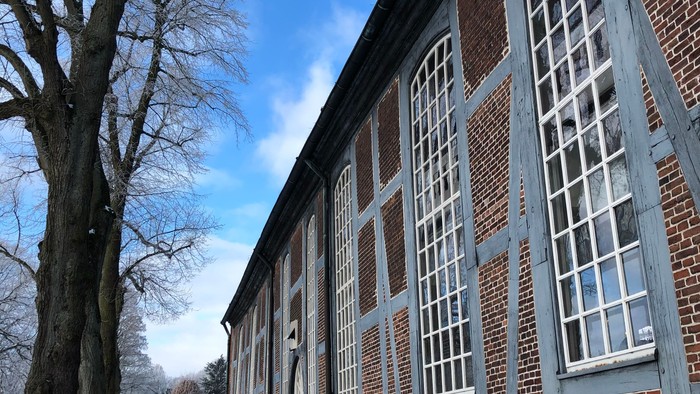 Altes Backsteingebäude mit weißen Fensterrahmen unter blauem Himmel
