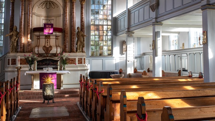 Innenraum einer Kirche mit Holzgestühl und Altarraum