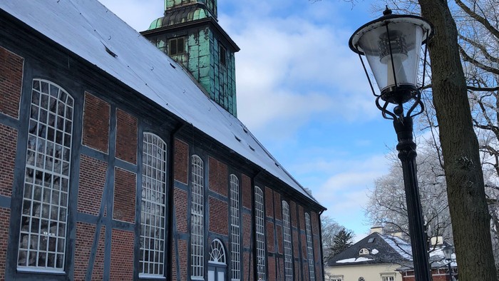 Schneebedeckte Straße mit Kirche und Bänken