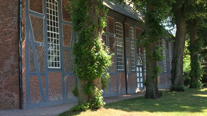 Altes Backsteingebäude mit blauen Fensterläden und Kletterpflanzen
