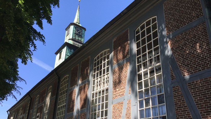 Historisches Backsteingebäude mit hohen Bogenfenstern und einem markanten Uhrturm.