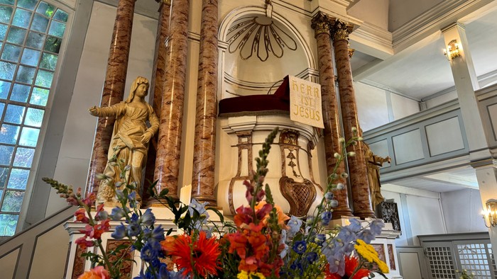 Eleganter Altar, geschmückt mit Statuen, verzierten Säulen und üppigen Blumenarrangements in einem prächtigen Kircheninnenraum.